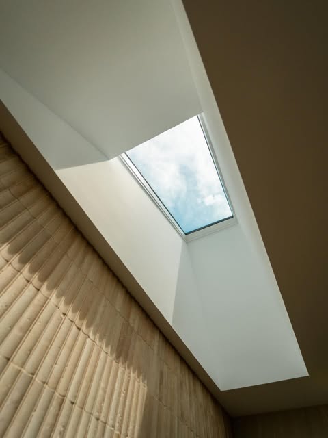 Skylight bringing daylight across a textured interior wall